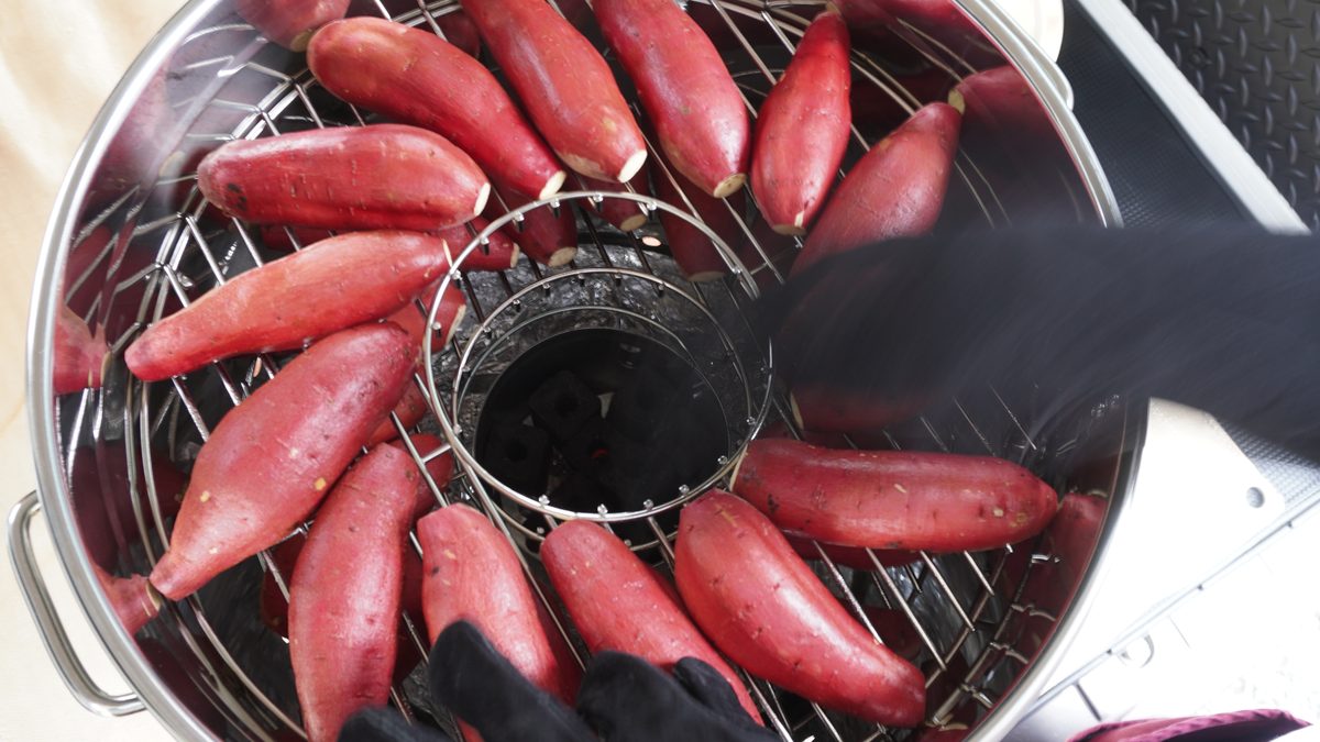 焼き網に生のさつまいもを放射状に並べていく手元