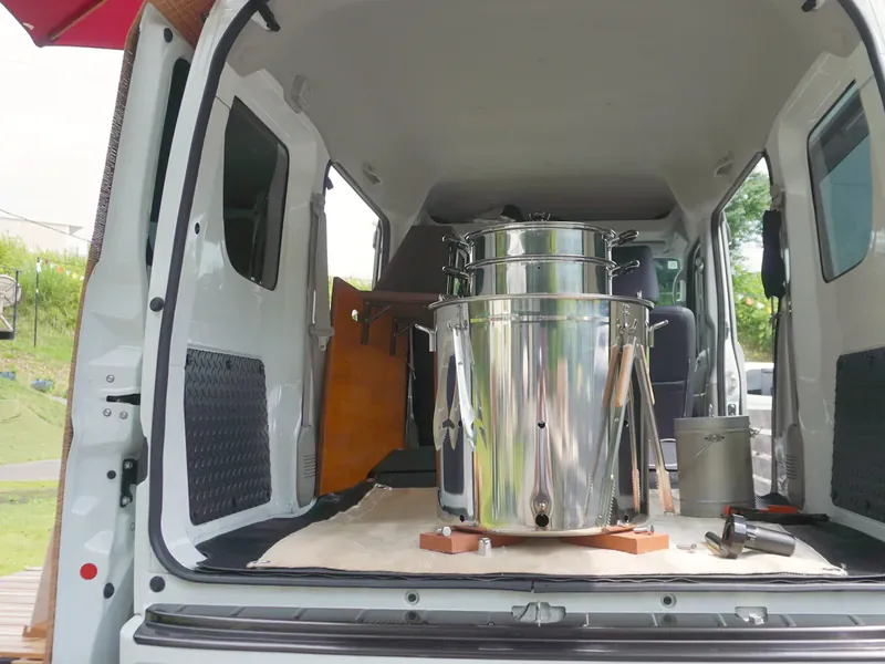 軽バンの荷台に積まれたステンレス製の焼き芋機